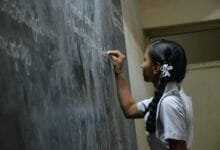 woman standing writing on black chalkboard